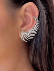 Close-up of an ear wearing a sparkling silver earring with a blurred background