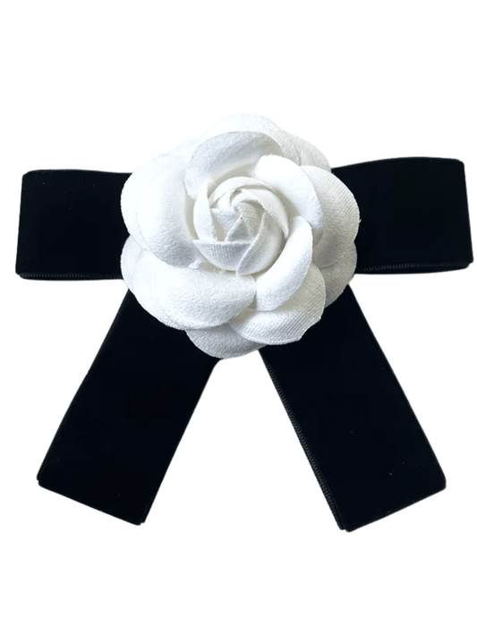 Fleur de Camélia Kathy Velvet Bow Ribbon Brooch featuring a black velvet ribbon with a white camellia flower appliqué and metal bar pin closure.