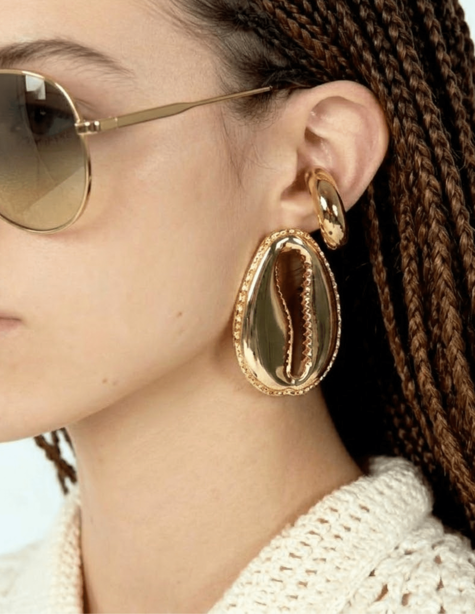 Gold-tone cowrie shell statement earrings worn on model