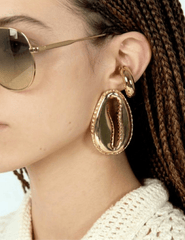 Gold-tone cowrie shell statement earrings worn on model