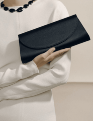 Model holding Hunting Season The Opera black satin clutch with elegant cream outfit