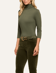 Angled view of L'AGENCE Aja fitted turtleneck in Army Green styled with tonal pants.