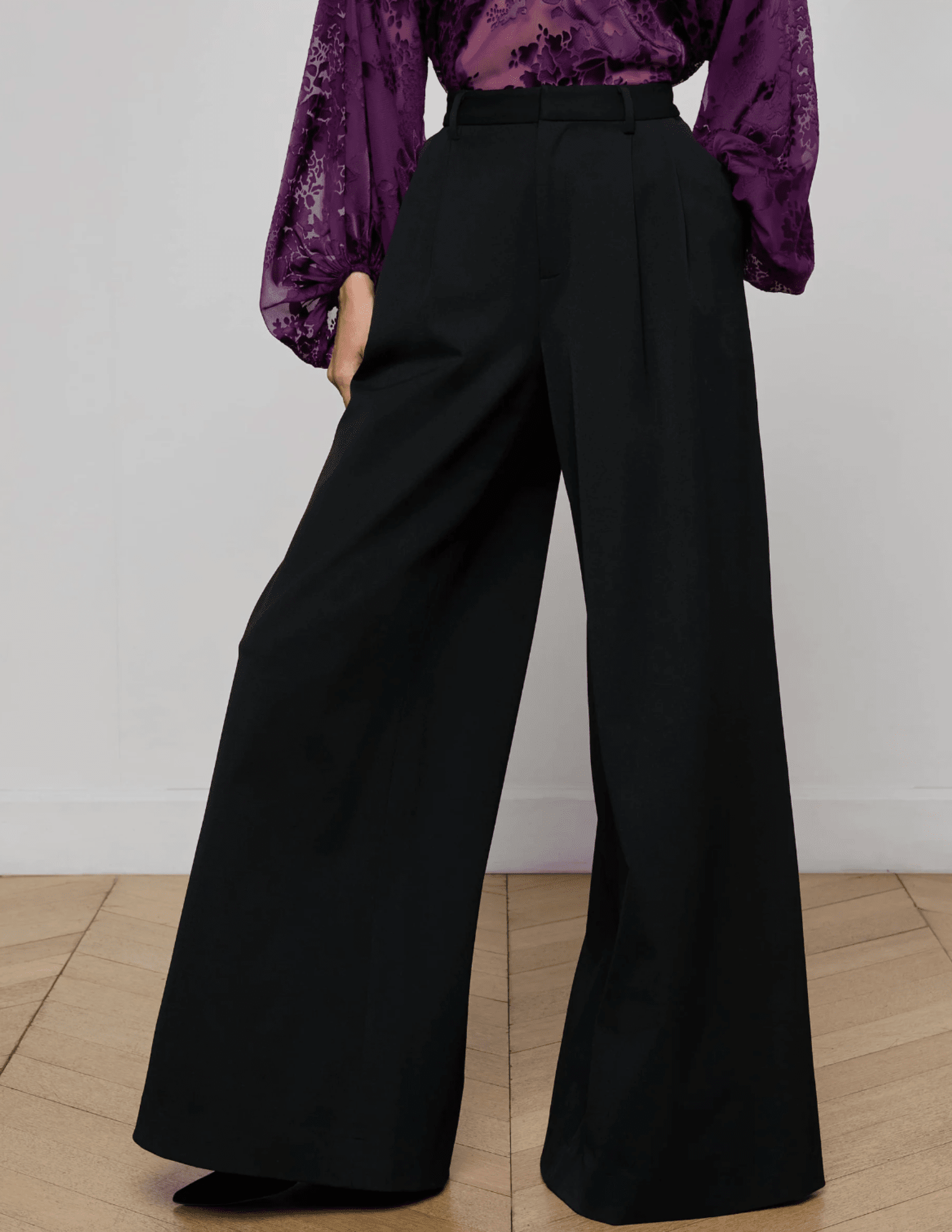 Model wearing L’AGENCE black wide leg trousers in stretch suiting fabric