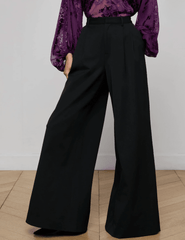 Model wearing L’AGENCE black wide leg trousers in stretch suiting fabric