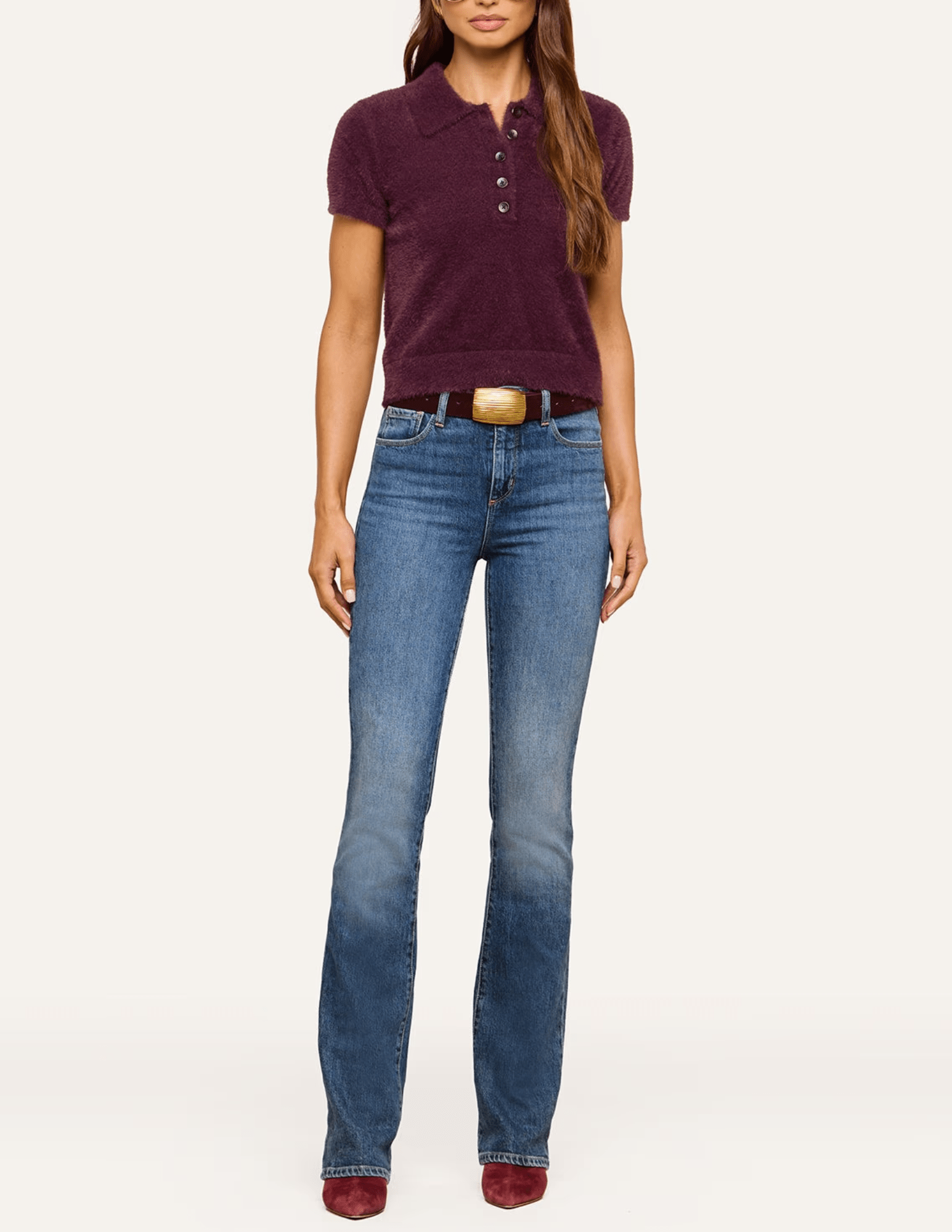 Model wearing L'AGENCE Cirrus Cropped Polo in Dark Plum styled with blue jeans, showing the short sleeves and cropped silhouette.