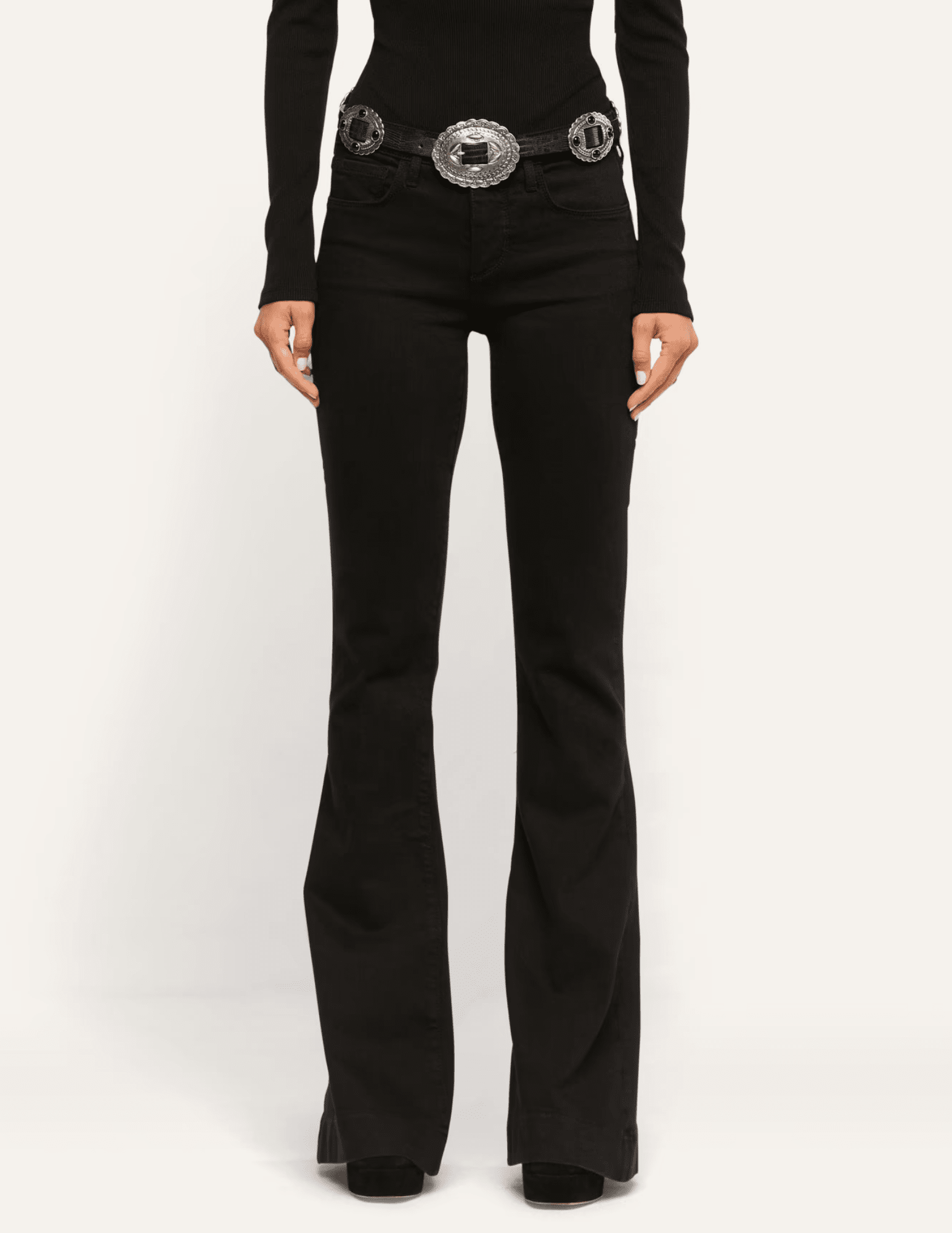 Model wearing L'AGENCE Her Story low-rise black flare jeans styled with a fitted black top and statement belt