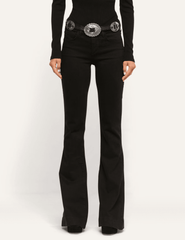 Model wearing L'AGENCE Her Story low-rise black flare jeans styled with a fitted black top and statement belt
