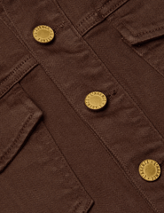 Front view of L’AGENCE Koda cropped denim jacket in brown with fringe and gold rivet buttons