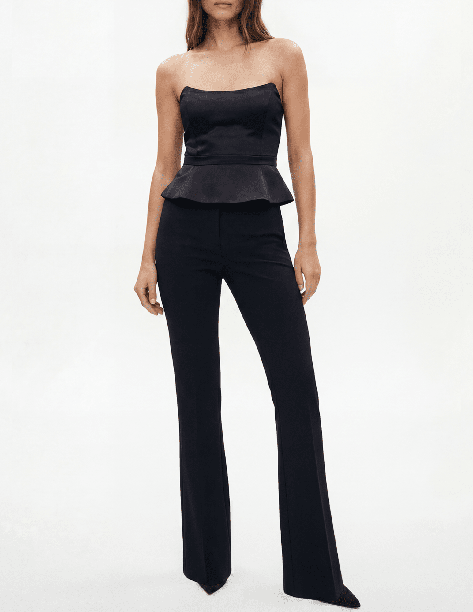 Model wearing L’AGENCE Meliora Corset Peplum Top in black with tailored black trousers.