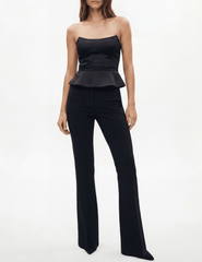 Model wearing L’AGENCE Meliora Corset Peplum Top in black with tailored black trousers.