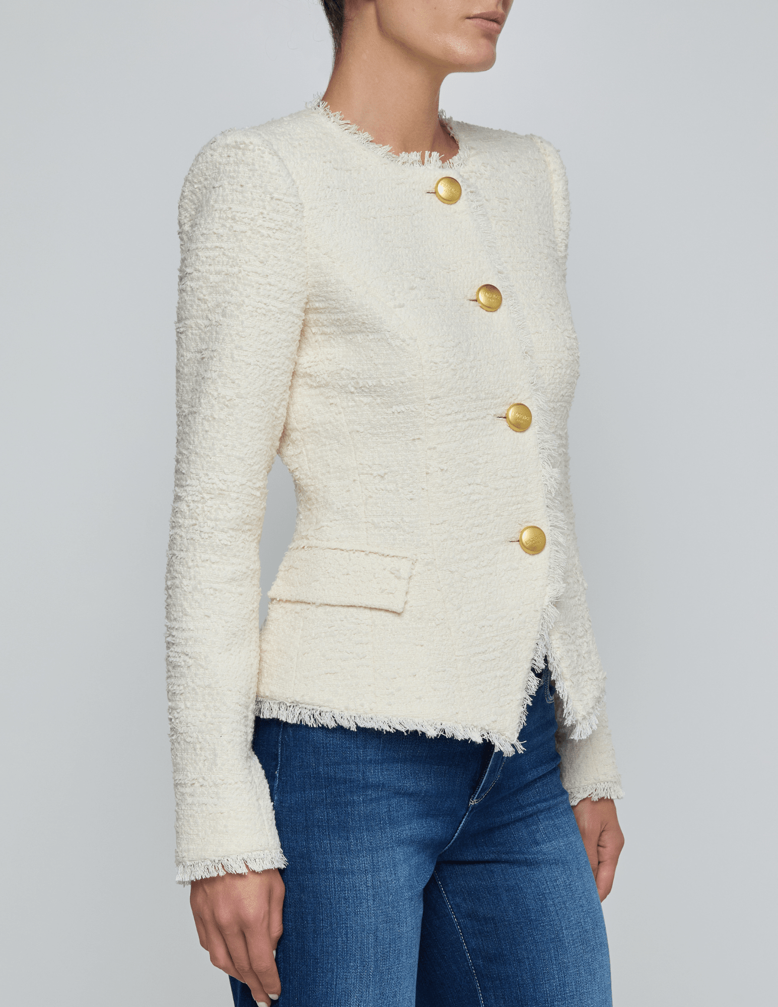 Side view of L’AGENCE Nerina collarless structured blazer in ivory with gold logo buttons