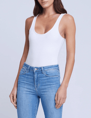 Model wearing L’AGENCE Nica Scoop Neck Bodysuit in white with light wash jeans, front view.