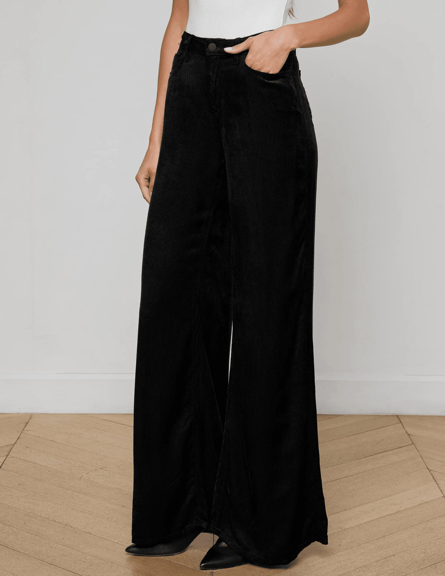 Model wearing L’AGENCE Quincy Wide Leg Corduroy Jeans in Black with high-rise waist.