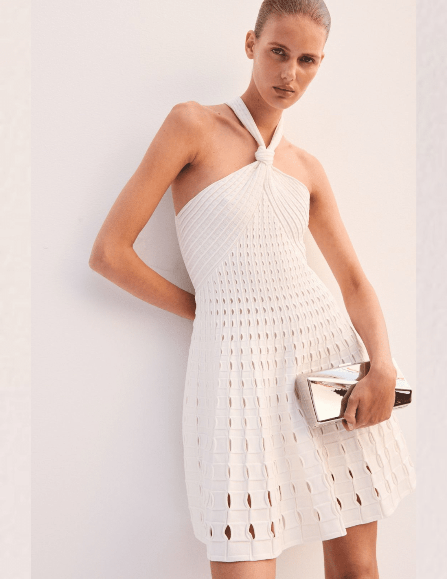 Model wearing Simkhai ivory halter knit mini dress